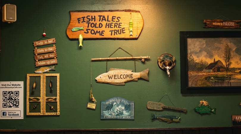 A green wall adorned with various fishing-themed signs, including "Fish Tales Told Here Some True".